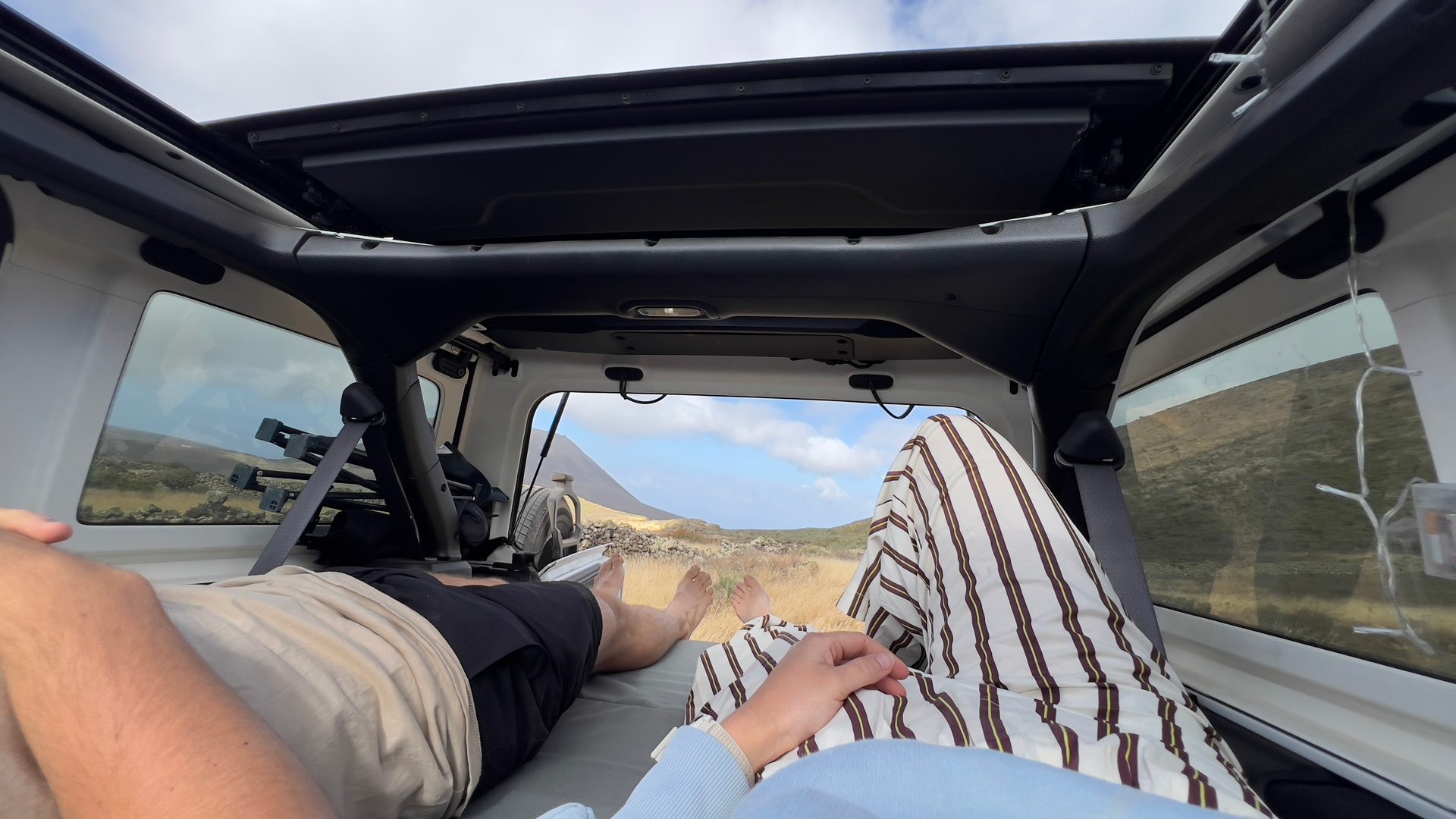 Dos personas descansando en la cama del kit camper forAll Pericamp con vistas al paisaje